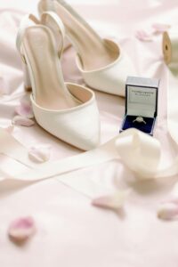 Close-up of elegant bridal shoes and a diamond ring for a wedding setting.