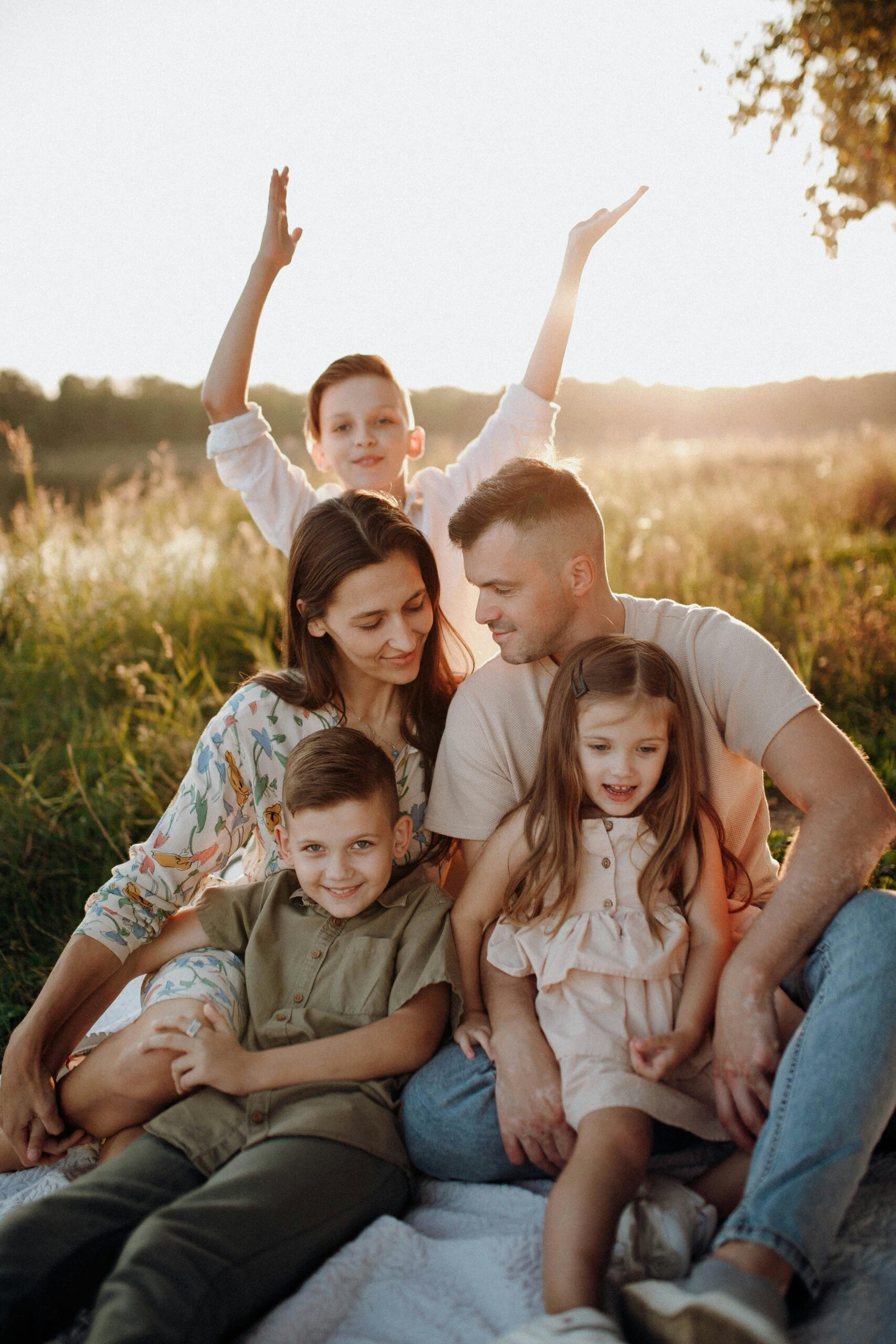 A joyful family sitting together outdoors in a sunny meadow, enjoying quality time.