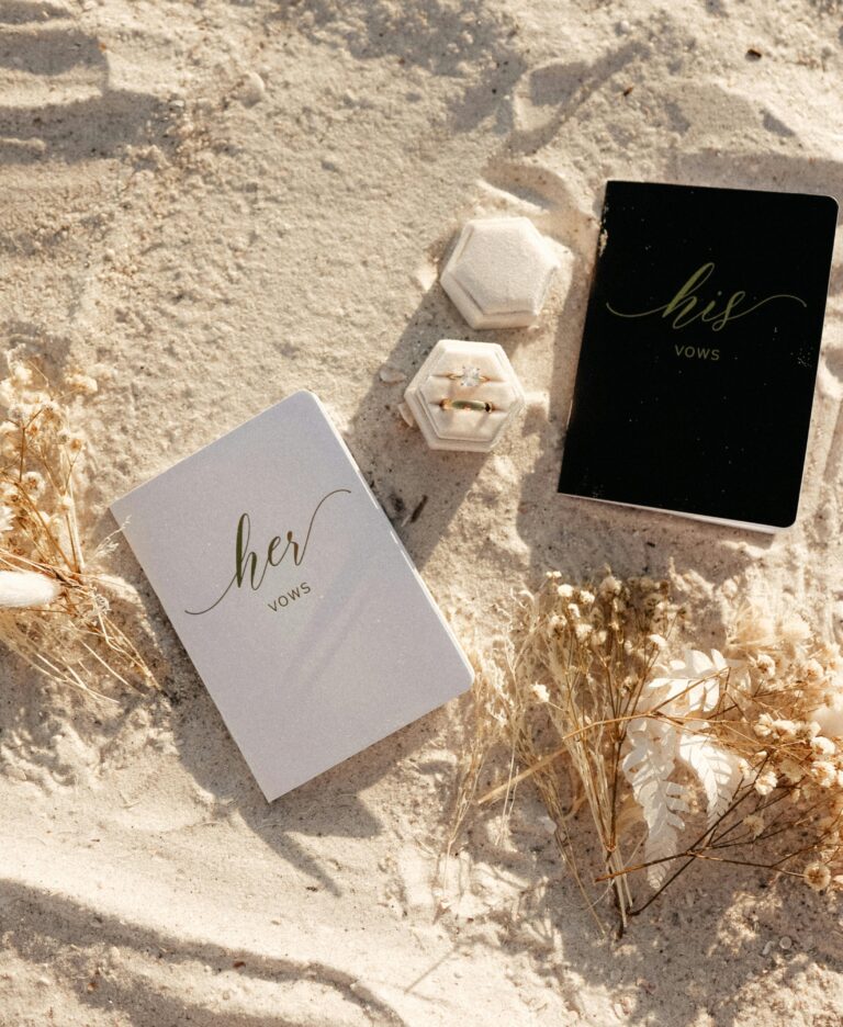 Elegant his and her vow books on a sandy beach, symbolizing a romantic elopement.