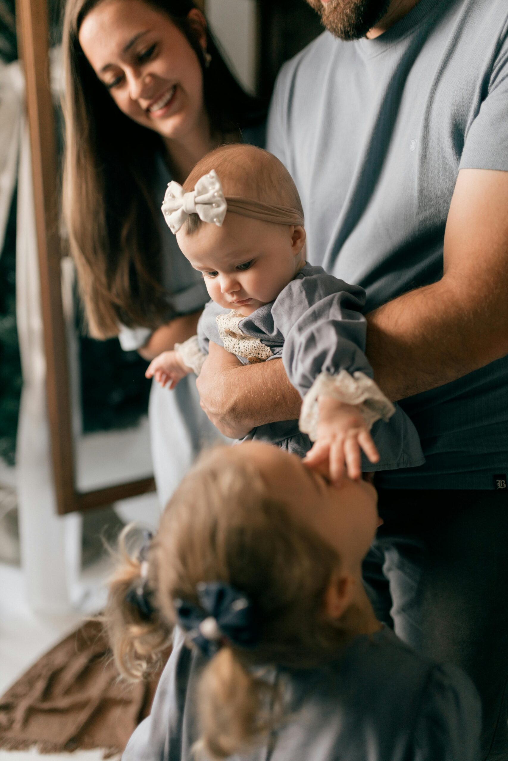 Joyful family interaction with baby and siblings indoors, capturing love and bonding.