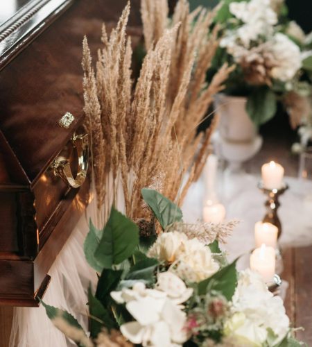 A serene funeral scene featuring a coffin surrounded by flowers and candles, emitting a respectful and peaceful atmosphere.